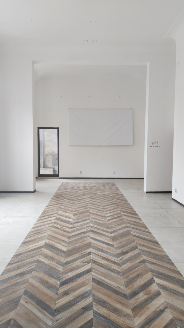 Fotografie interiéru budovy s nápisem 'TOILETS' a symbolem pro toalety na pravé stěně.