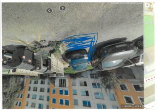 Fotografie z mapových podkladů (Google Street View) zachycující parkoviště, auty zaparkovaná u bytového domu, popelnice a modře označenou oblast.