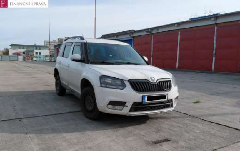 Fotografie bílého osobního automobilu značky Škoda (model Yeti) zaparkovaného na betonové ploše před budovou. V levém horním rohu je logo 'F. FINANČNÍ SPRÁVA'.
