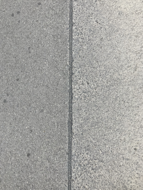 Detailní fotografie povrchu (pravděpodobně betonový chodník nebo vozovka), která může být součástí fotodokumentace k žádosti o stavební povolení nebo opravu komunikace.