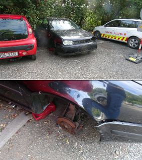 Fotografie z místa (pravděpodobně dokumentace k odtahu vozidla): Na snímku je zachycen nepojízdný černý automobil (Volkswagen Golf) bez kol, podepřený plastový…