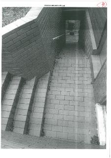 Fotografie exteriéru budovy, konkrétně schodiště vedoucího k podzemnímu vstupu s mříží. V horní části obrázku je ručně psané označení '4'. V záhlaví je uveden…
