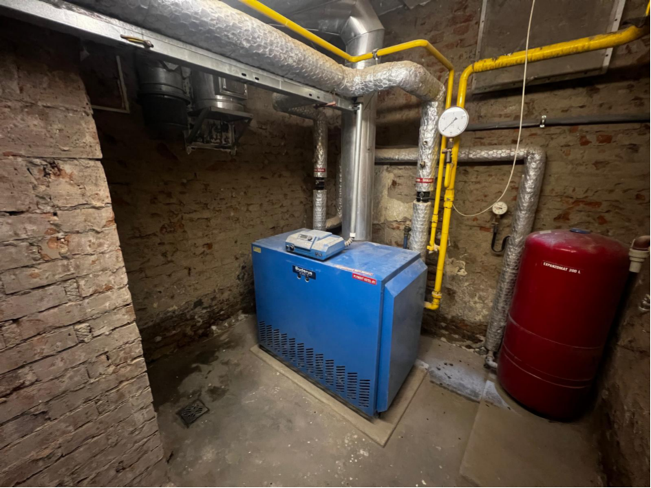 Fotografie technického zázemí budovy s plynovým kotlem a expanzní nádobou.