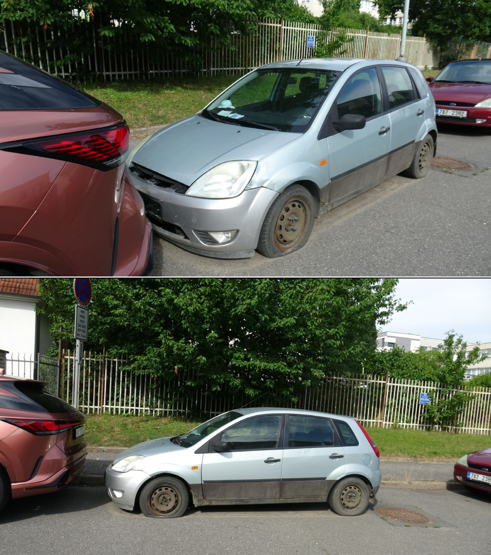 Fotografie dokumentující špatné parkování vozidla (stříbrný Ford Fiesta) s vypuštěnou pneumatikou, které stojí v těsné blízkosti jiného vozidla a v blízkosti dopravní značky zákazu zastavení (značka je viditelná v dolní části obrázku). Na registrační značce červeného vozidla vpravo je čitelné '7A7 2382'.