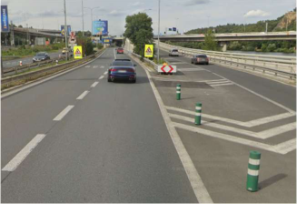 Fotografie z pohledu řidiče na dopravní situaci na komunikaci, pravděpodobně jako podklad pro dopravní značení nebo stavební povolení v silničním provozu.