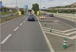 Fotografie z pohledu řidiče na dopravní situaci na komunikaci, pravděpodobně jako podklad pro dopravní značení nebo stavební povolení v silničním provozu.