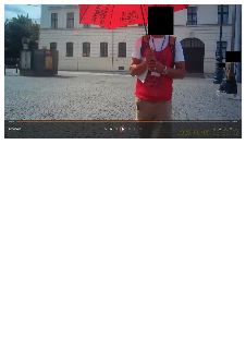 Muž stojící na dlážděném náměstí s červeným deštníkem, na němž je zrcadlově obrácený nápis 'PRAGUE PANORAMA KAMELOT', na červené vestě nápis 'PRAGUE PANORAMA K…