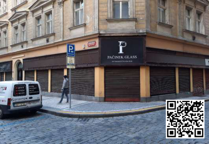Fotografie budovy s obchodem 'PAČINEK GLASS'. Na budově je umístěna dopravní značka 'P' (parkoviště) s dodatkovou tabulkou a uliční tabulka s nápisem 'KARMELITSKÁ'. Na dodávce vlevo je nápis 'print copy scan' a 'proimpe'.