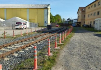 Fotografie pozemku s železniční vlečkou a okolní zástavbou.