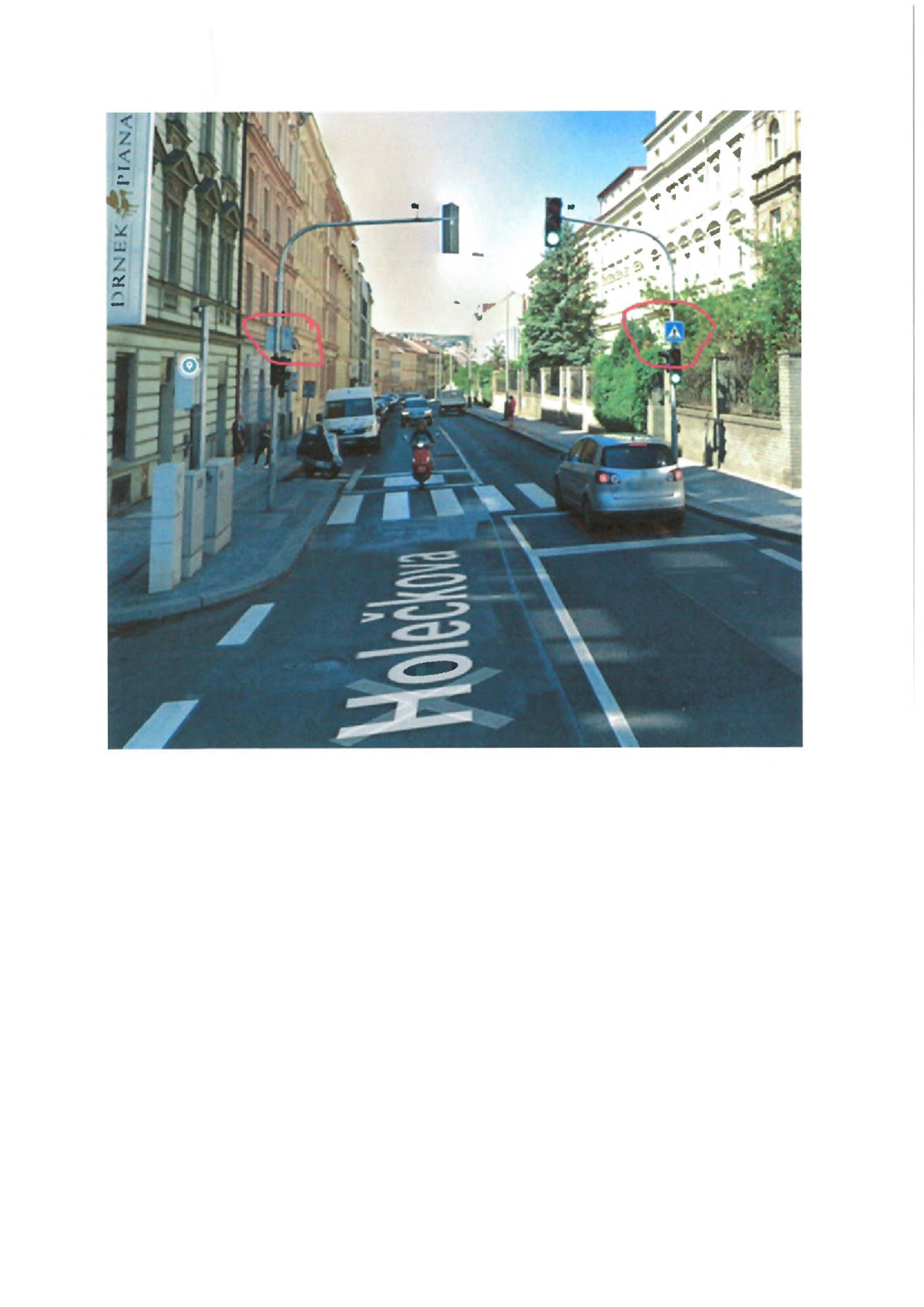 Fotografie ulice Holečkova v Praze. Na vozovce je velkým bílým písmem napsán název ulice 'Holečkova'. Na levé straně budovy je svislý nápis 'DRNEK PIANA'. V pravé části obrázku je na sloupu dopravní značka označující přechod pro chodce.