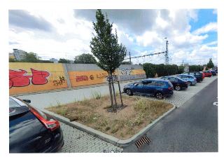 Fotografie exteriéru zachycující parkoviště podél betonové zdi s graffiti. Na zdi je čitelný nápis 'LLV'. V pravém dolním rohu je vodoznak 'Google Maps'.