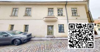 Fotografie budovy s dlážděnou ulicí a zaparkovaným autem v popředí