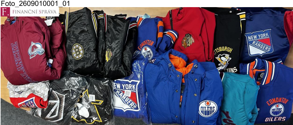 Fotografie zabaveného zboží (sportovní bundy a oblečení s logy hokejových týmů NHL), dokumentace Finanční správy ČR. Na obrázku jsou viditelné nápisy a loga týmů: AVALANCHE, BOSTON (B), CHICAGO BLACKHAWKS, EDMONTON OILERS, NEW YORK RANGERS, PITTSBURGH PENGUINS.