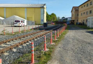 Fotografie pozemku s železniční vlečkou a přilehlými budovami.