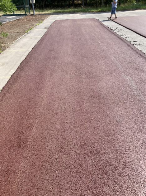 Fotografie nově položeného povrchu (pravděpodobně sportovní dráha nebo chodník) v rámci stavebního projektu.