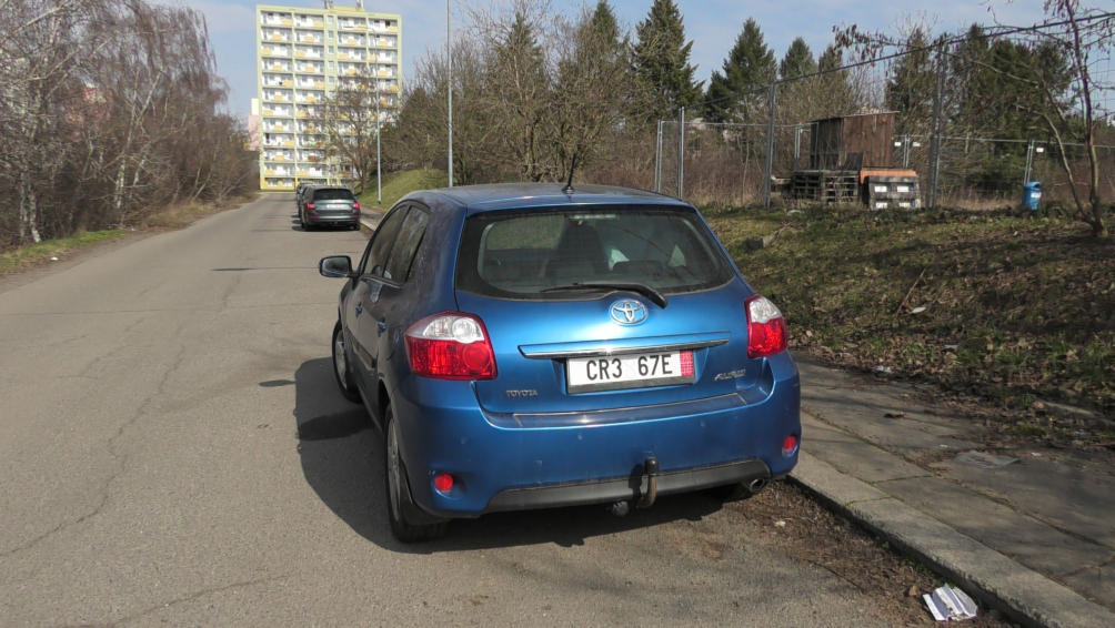 Fotografie exteriéru (automobilu) na pozemku, pravděpodobně jako součást dokumentace k řízení.