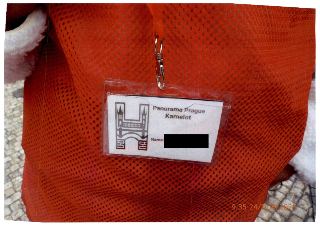 Jmenovka na krk, na které je nápis: 'Panorama Prague', 'Kamelot', a vlevo je grafické logo zobrazující siluetu budovy/mostu s věžemi.
