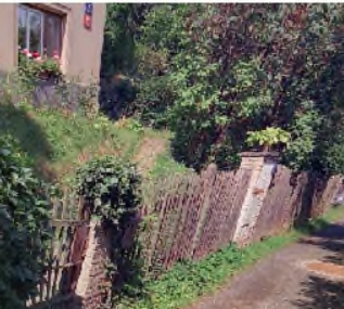 Fotografie exteriéru budovy a přilehlého pozemku s oplocením.
