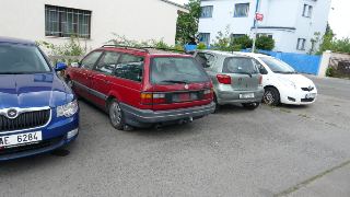 Fotografie parkoviště s auty. Na modrém autě vlevo je viditelná registrační značka AE 6284, na šedém autě uprostřed 3S5 3397 a na bílém autě vpravo 4J5 3100.