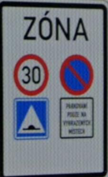 Dopravní značka označující zónu s omezením: ZÓNA, rychlostní limit 30 km/h, zákaz stání, upozornění na zpomalovací práh a text 'PARKOVÁNÍ POUZE NA VYHRAZENÝCH MÍSTECH'.