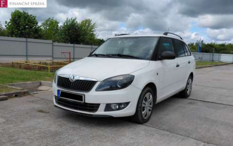 Fotografie bílého osobního automobilu značky Škoda (model Fabia Combi) zaparkovaného na zpevněné ploše. V levém horním rohu je logo Finanční správy.