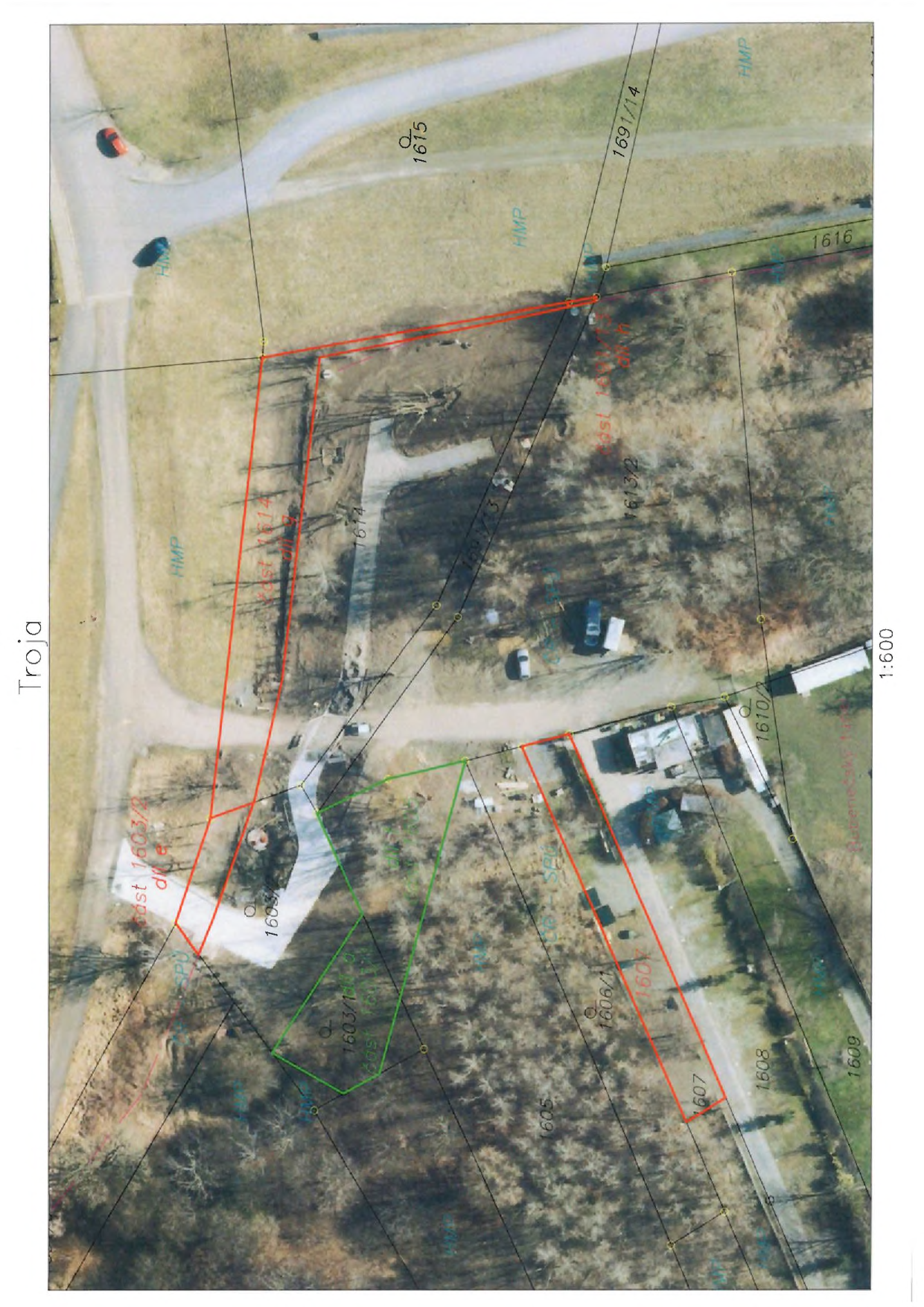 Katastrální situační mapa oblasti Troja s vyznačenými parcelami a jejich částmi. Čitelné údaje: 'Troja', měřítko '1:600'. Vyznačená čísla parcel: 1615, 1691/14, 1614, 1613/2, 1603/2, 1603/1, 1606/1, 1607, 1608, 1609, 1610/2. Texty u parcel: 'část 1603/2', 'část 1614', 'část 1603/1', 'část 1606/1'. V mapě je patrné ortofoto s překrytím hranic pozemků a technickým zákresem (červené a zelené linie).